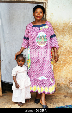 Pregnant black African mother and baby girl in front of their house