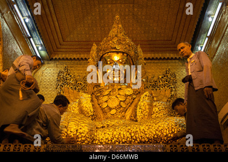 Worshippers applying gold leaf to the Mahamuni Buddha, Mahamuni Pagoda, Mandalay, Myanmar, (Burma) Stock Photo
