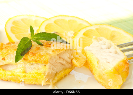 Fish fillets fried in batter with lemon and basil on a plate Stock Photo
