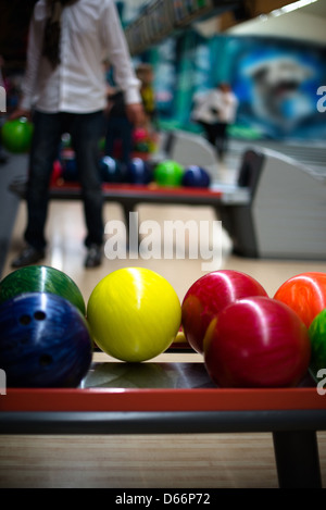 Bowling scene: Colorful balls in the foreground and casual man picking bis ball in the background Stock Photo