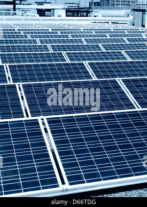 Array of solar panels in rows on a roof of a building in a city Stock Photo