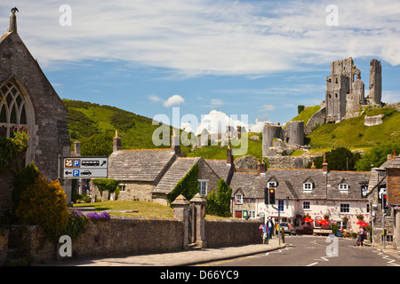 Corfe Castle ruins tower above The Greyhound pub and Bankes Arms Hotel in Corfe Castle village, Dorset, England, UK Stock Photo