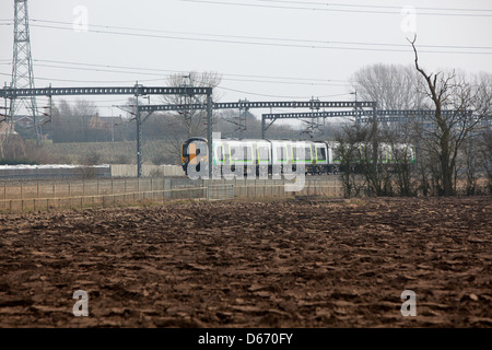 A London Midland train running through the countryside adjacent to farmland. Stock Photo