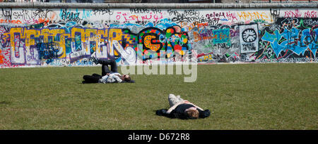Berlin, Germany. 14 April 2013. Young people lie on a meadow at the backside of the East Side Gallery and enjoy the sunhsine. Photo: WOLFRAM STEINBERG/Alamy Live News Stock Photo
