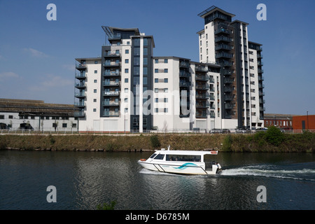 Cardiff Bay Aquabus passing a modern riverside tall residential housing building block on the river Taff Wales UK water transport Stock Photo