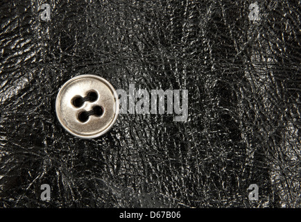 Metal button on shiny black leather with detailed texture. Stock Photo