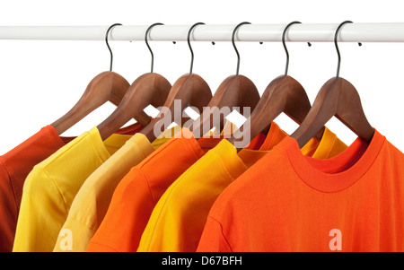 Choice of yellow and orange casual shirts on wooden hangers, isolated on white. Stock Photo