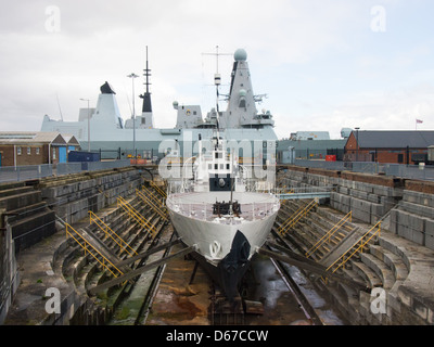 first world war warship M33 in dry dock at Portsmouth Historic Dockyard, with the modern Type 45 HMS dauntless in the background Stock Photo