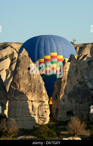 Hot air balloon manoeuvres between tuff rock cones in the rock sites of Cappadocia, Göreme, Turkey Stock Photo
