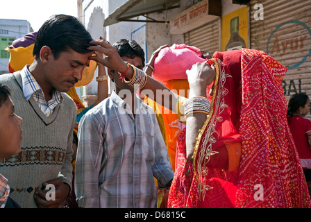 Indian woman putting a tikka (bindi) on the foreground of a relative. Welcome ritual. Pushkar. India Stock Photo