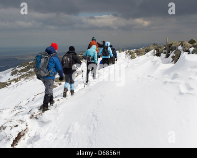 Group of Ramblers walking on ridge of Tal-y-Fan mountain in deep snow in mountains of Snowdonia, North Wales, UK, Britain Stock Photo