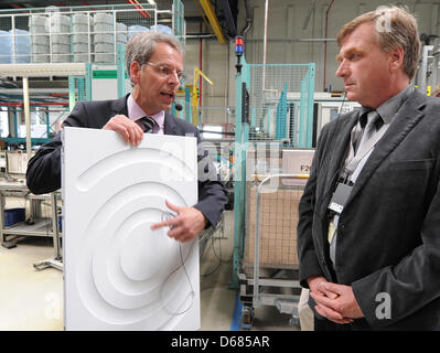 Site manager Tilmann Dominik of the Bosch Siemens Hausgeraete GmbH factory in Nauen (l) shows a side panel of a washing machine to Ralf Christoffers, minister of economics of the federal state Brandenburg, (r) in Nauen, Germany, 4 July 2012. Tilmann Dominik took a decisive role in the successful development of the BSH factory in New Bern, North Carolina, USA, where he served as a s Stock Photo