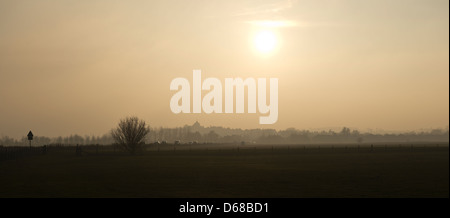 View across open countryside towards the harbour town of Rye, the hilltop Church tower dominating the landscape against hazy sky Stock Photo