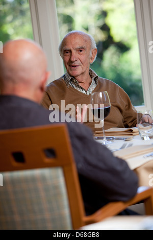 Elderly man having a meal with a friend. Chatting, happy and enjoying himself. Stock Photo