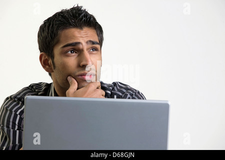 Man thinking while working on laptop Stock Photo