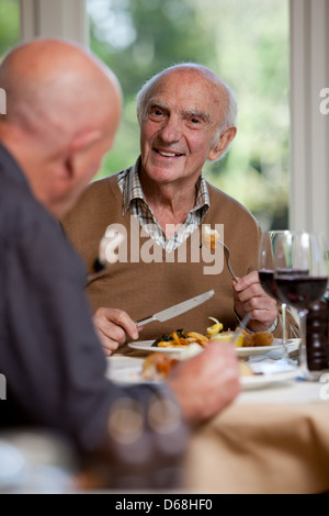 Elderly man having a meal with a friend. Chatting, happy and enjoying himself. Stock Photo