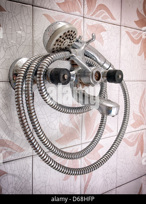 An old shower with cracked tiles in the background. Stock Photo