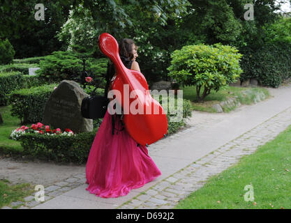A female musician with a violoncello arrives at the 12th summer concert of Saint Severin church in Keitum on Sylt, Germany, 27 July 2012. The concert is organized by the German foundation Musikleben 'music life'. Photo: Jens Kalaene Stock Photo