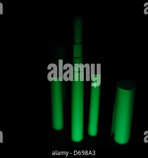 An experimental photo captured with a Nikkor 35mm f/1.4 AI-S lens, showing a dark, moody atmosphere with a glowstick against paper. The wide-open aperture creates a unique light effect and emphasizes the contrast between light and shadow. Stock Photo