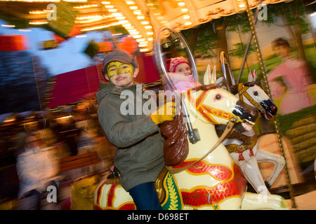 A boy rides a fair carousel evening Stock Photo