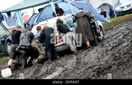 Festival visitors try to push a car out of the mus on the camping site of the Wacken Open Air Festival in Wacken, Germany, 04 August 2012. The world's biggest heavy metal festival takes place in Wacken from 02 till 04 August 2012. Photo: DANIEL REINHARDT Stock Photo