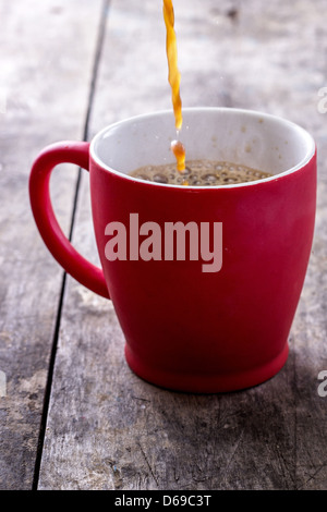 Pouring a Fresh Cup of Brewed Coffee against wooden Background. Studio shot. Stock Photo