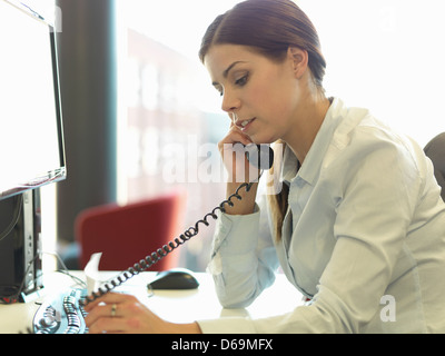 Businesswoman talking on phone at desk Stock Photo