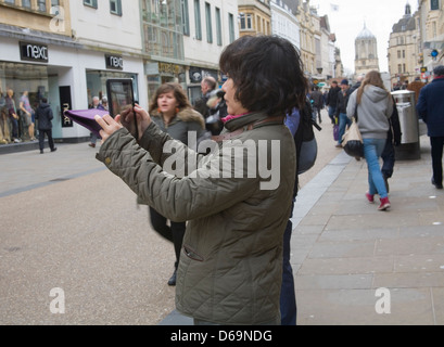 Oxford Oxfordshire Asian woman using IPad to take photo of city centre building Stock Photo