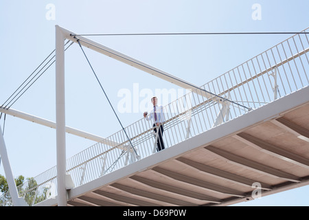 Businessman walking on urban bridge Stock Photo