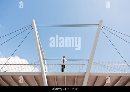 Businessman standing on urban bridge Stock Photo