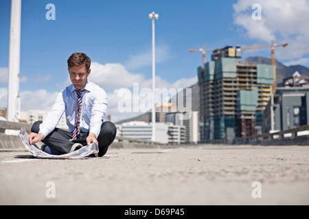 Businessman reading on city street Stock Photo