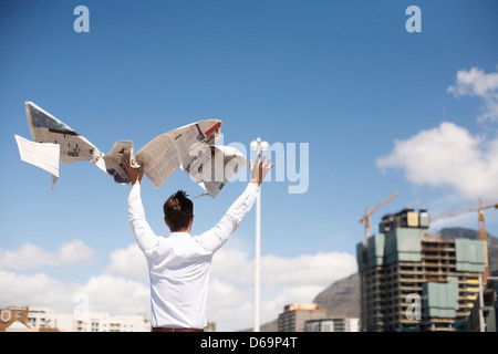 Businessman throwing newspaper in air Stock Photo