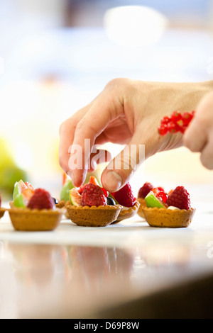 Baker making fruit tarts in kitchen Stock Photo