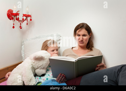 Mother reading to daughter in bed