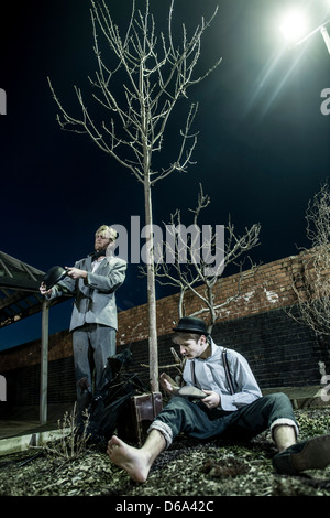 2 actors performing as Vladimir & Estragon in Samuel Beckett's classic play 'Waiting for Godot' in a deserted carpark at night Stock Photo