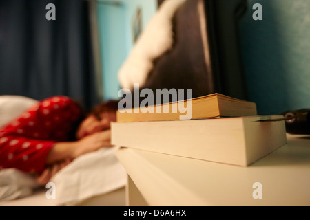 paperback books on bedside table of early twenties woman in bed in a bedroom Stock Photo