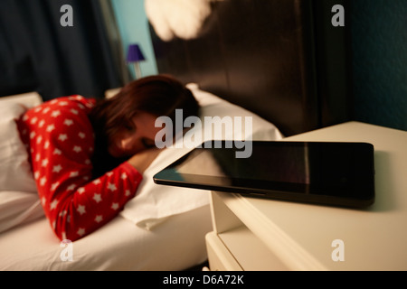 tablet computer on bedside table of early twenties woman in bed in a bedroom Stock Photo