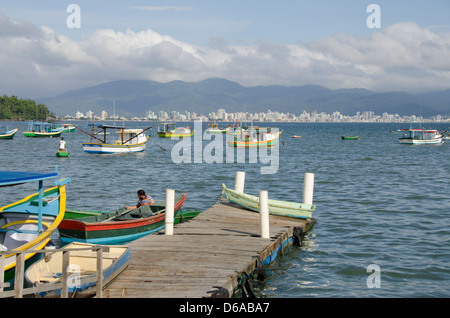 Brazil, state of Santa Catarina, Porto Belo. Colorful local fishing boats with city skyline in distance. Stock Photo