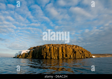 Norway, Svalbard Archipelago, Spitsbergen. Clouds flow over a rock island along the coast in summer. Stock Photo