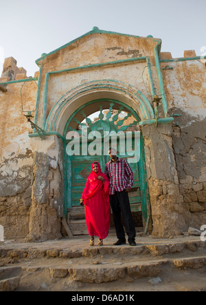 Couple In Front Of A Huge Green Door Of A Ruined Ottoman Coral Buildings, Suakin, Sudan Stock Photo