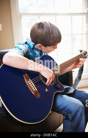 Boy playing guitar on sofa Stock Photo