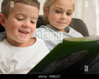 Children reading together on sofa Stock Photo