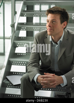 Businessman sitting on steps in office Stock Photo