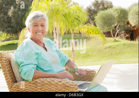 Older woman using laptop outdoors Stock Photo