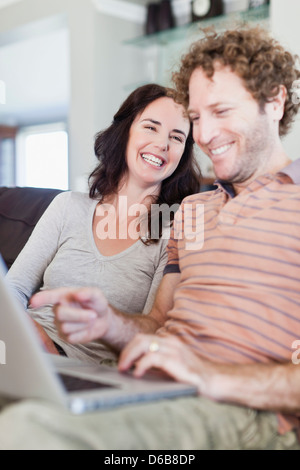 Couple using laptop together on sofa Stock Photo
