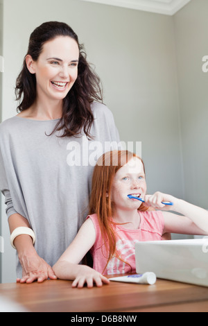 Mother watching daughter brush teeth Stock Photo