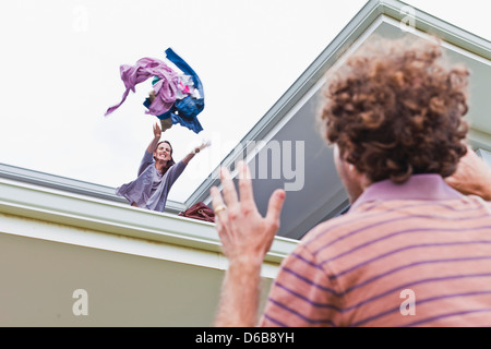 Woman throwing out boyfriends clothes Stock Photo