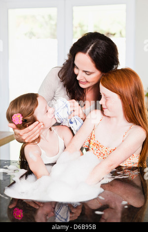 Mother wiping daughters face in kitchen Stock Photo