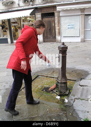 Teenage girl fills water bottle in Venice Italy Stock Photo