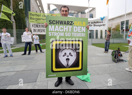 Chairman of the Greens Cem Ozedmir holds a sign asking the governing coalition to reduce energy prices before an energy summit with the government, employers and unions in Berlin, Germany, 28 August 2012. Topics of the summit include the developments concerning the costs of the energy turnaround. Photo: KAY NIETFELD Stock Photo